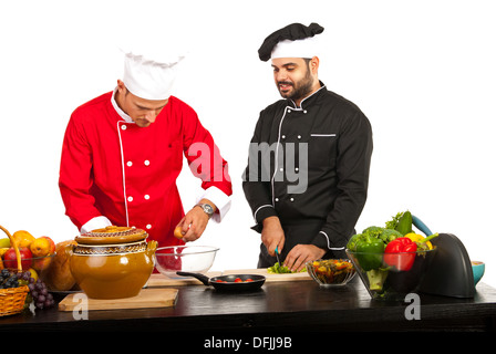 Zwei Köche, die Zubereitung von Speisen in der Küche vor weißem Hintergrund Stockfoto