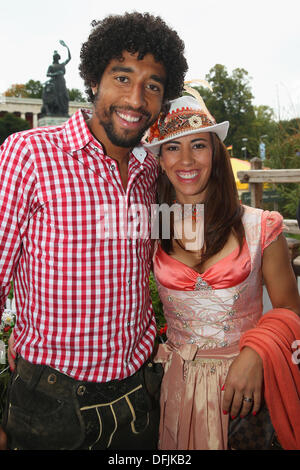 München, Deutschland - Oktober 06: Dante Bayern Muenchen Posen mit Jocelina vor dem Ensemble der Bavaria-Statue, Sandgusstechnik eine monumentale Bronze Statue aus dem 19. Jahrhundert und die Hall Of Fame (Fresko) während dem Oktoberfest 2013 Bierfest am Kaefers Wiesenschaenke am 6. Oktober 2013 in München. Die Bavaria ist die weibliche Personifizierung der bayerischen Heimat und durch Verlängerung, seine Kraft und Herrlichkeit. Bildnachweis: Kolvenbach/Alamy Live-Nachrichten Stockfoto