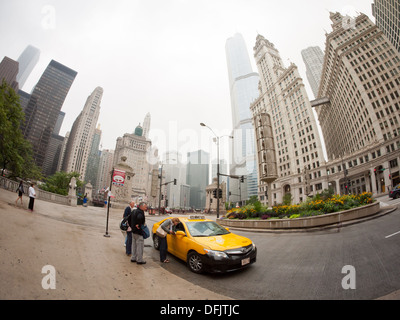 Ein Fischauge Blick auf drei Menschen fangen ein Taxi an der North Michigan Avenue in Chicago, Illinois, an einem bewölkten, trüben Tag. Stockfoto