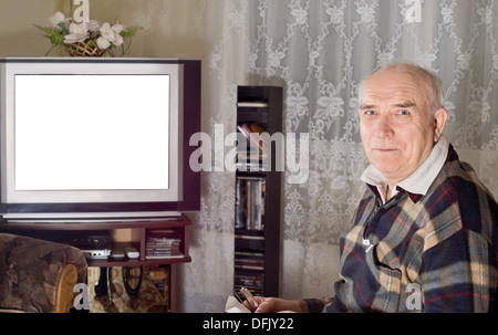 Ältere Menschen vor dem Fernseher mit einem leeren weißen Bildschirm sichtbar am Set wie er wendet sich in die Kamera Lächeln Stockfoto