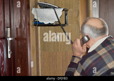 Älterer Mann am Telefon sitzen mit dem Rücken zur Kamera hält den Hörer an sein Ohr sprechen Stockfoto
