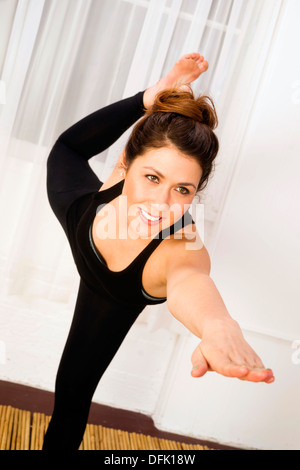 Attraktive Frau gleicht sich auf Bambusmatte im Studio Yoga zu praktizieren Stockfoto