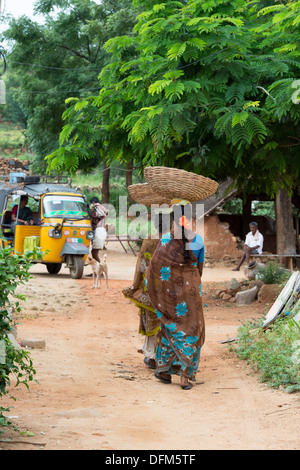 Indische Frauen in einem indischen Dorf tragen Körbe auf dem Kopf gehen. Andhra Pradesh, Indien Stockfoto