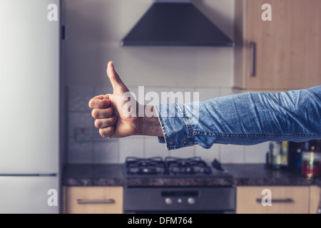 Junger Mann mit Daumen oben in Küche Stockfoto