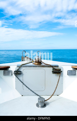 Der Bogen eines Passagiers Kreuzfahrt Bootsmessen seiner rostigen Anker-Kette, Stollen und Winde unter blauem Himmel und weit entfernten Inseln. Stockfoto