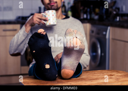 Junger Mann mit getragenen Socken am Tisch Stockfoto