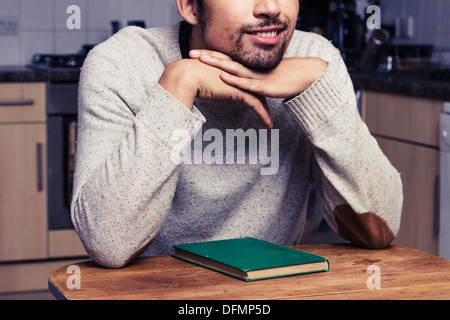 Lächelnder junger Mann mit Buch in Küche Stockfoto