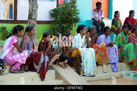 Indische Frauen in ländlichen Gebieten und Mädchen beten an der Sri Sathya Sai Baba mobile aufsuchende Krankenhausklinik. Andhra Pradesh, Indien Stockfoto