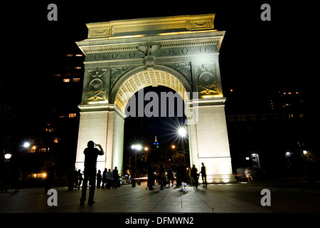 Mann mit dem Fotografieren von New York Citys Washington Square Arch beleuchtet in der Nacht von innen Washington Square Park Stockfoto