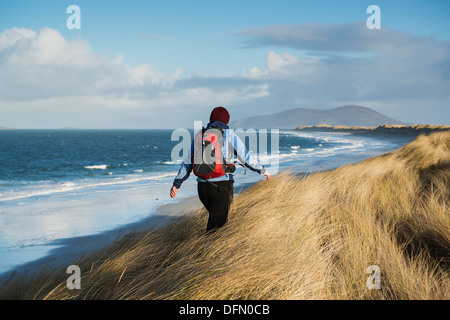 Frau geht durch Küsten Dünengras am Weststrand, Berneray, äußeren Hebriden, Schottland Stockfoto