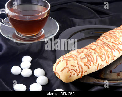 Heißen Tee mit Käse Brot und weißen Steinen auf schwarzem Hintergrund Stockfoto