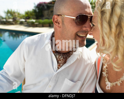 Ein gut gebauter junger Mann berührt die Nasenspitze einer hübschen Frau durch seine Nasenspitze an der Seite eines Schwimmbades in San Diego. Stockfoto