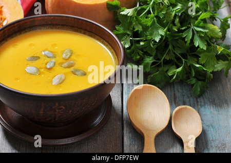 Schüssel mit Kürbissuppe auf rustikalen Holztisch. Stockfoto