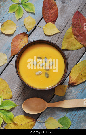 Schüssel mit Kürbissuppe auf rustikalen Holztisch. Stockfoto