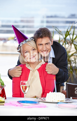 Glücklicher erwachsener Mensch feiert Geburtstag mit seiner älteren Mutter Stockfoto