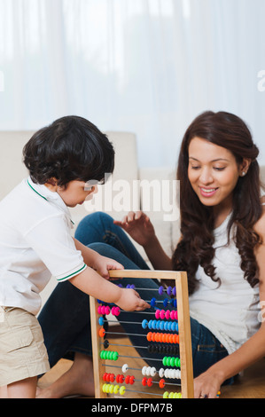 Baby Junge spielt mit einem Abakus mit seiner Mutter neben ihm Stockfoto