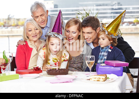 Glückliches Mädchen Ausblasen der Kerzen auf Geburtstagsparty mit ihrer Familie Stockfoto