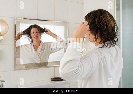 Eine Frau ist Blick in den Spiegel im Bad und ein "bad Hair Day". Stockfoto