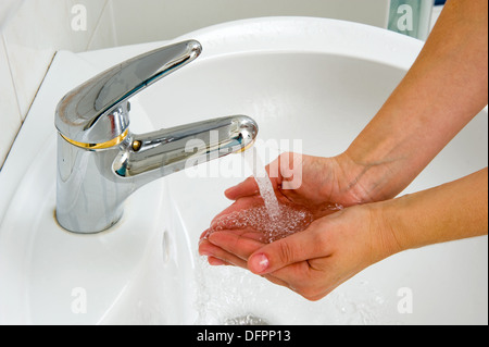 Eine Frau holt Wasser aus einem Hahn in ihren Händen Stockfoto