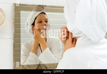 Eine Frau ist die kleine Haare aus ihrem Schnurrbart vor einem Spiegel enthaaren. Stockfoto