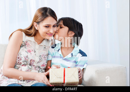 Junge küssen seine Mutter hält ein Geschenk Stockfoto