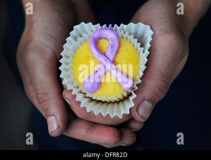 Luftfahrt Elektriker Mate 3. Klasse Sean Latham, befestigt an Hubschrauber Mine Gegenmaßnahmen Squadron (HM) 15 "Blackhawks" hält einen lila Band Cupcake zur Unterstützung der Domestic Violence Awareness Month. Der US-Marine ist häusliche Gewalt aufmerksam beobachten. Stockfoto