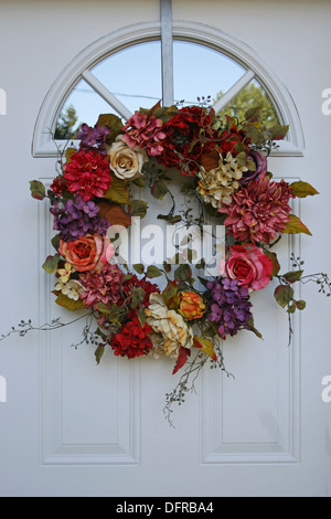 Kranz aus Blumen auf eine weiße Tür Stockfoto