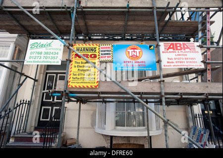 Builders Werbetafeln auf Gerüsten auf eine 1822 gebaut Regency House unter Restaurierung im Zentrum von Brighton. Stockfoto