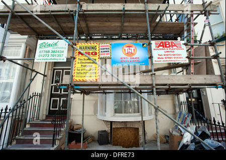 Builders Werbetafeln auf Gerüsten auf eine 1822 gebaut Regency House unter Restaurierung im Zentrum von Brighton. Stockfoto