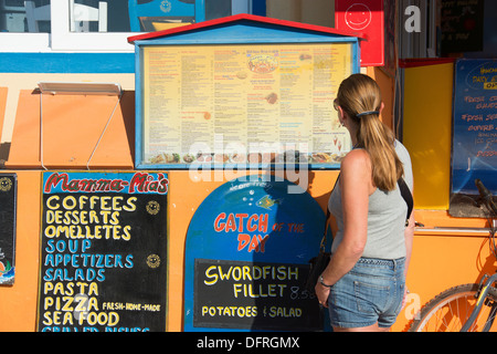 SANTORINI (THIRA), KYKLADEN, GRIECHENLAND. Ein Urlauber eine Speisekarte an Bord vor einem Restaurant in dem Badeort Kamari durchlesen. Stockfoto