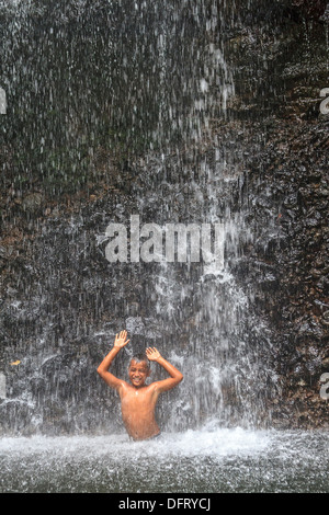 Einheimische junge spielt im kaskadierenden Spray von Sipyen Wasserfall, Kosrae, Mikronesien. Stockfoto