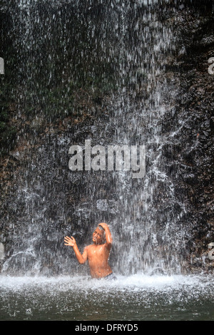 Einheimische junge spielt im kaskadierenden Spray von Sipyen Wasserfall, Kosrae, Mikronesien. Stockfoto