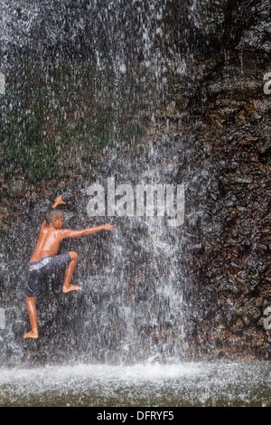 Einheimische junge spielt im kaskadierenden Spray von Sipyen Wasserfall, Kosrae, Mikronesien. Stockfoto