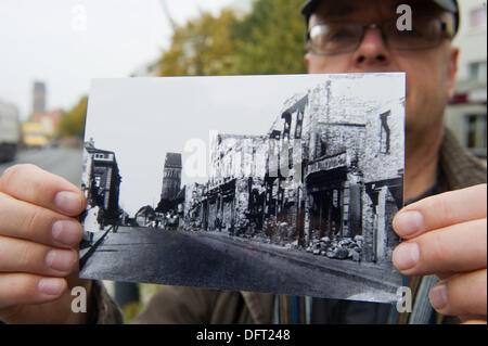 Anklam, Deutschland. 8. Oktober 2013. Mitarbeiter des städtischen Museums in Anklam, Peer Wittig, zeigt ein Bild von der Steinstraße Straße nach der Bombardierung im Jahre 1943 in Anklam, Deutschland, 8. Oktober 2013. Am 9. Oktober 2013 erinnert an Anklam, die Bombardierung der Stadt vor 70 Jahren. Die Bombardierung durch US-Flugzeuge am 9. Oktober 1943 vor allem konzentrierte sich auf die Arado-Flugzeugwerke. Foto: STEFAN SAUER/Dpa/Alamy Live News Stockfoto