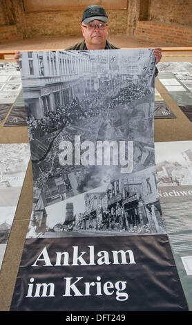 Anklam, Deutschland. 8. Oktober 2013. Mitarbeiter des städtischen Museums in Anklam, Peer Wittig, hält das Banner der Sonderausstellung "Anklam im Krieg - eine Chronik", in Anklam, Deutschland, 8. Oktober 2013. Am 9. Oktober 2013 erinnert an Anklam, die Bombardierung der Stadt vor 70 Jahren. Die Bombardierung durch US-Flugzeuge am 9. Oktober 1943 vor allem konzentrierte sich auf die Arado-Flugzeugwerke. Foto: STEFAN SAUER/Dpa/Alamy Live News Stockfoto