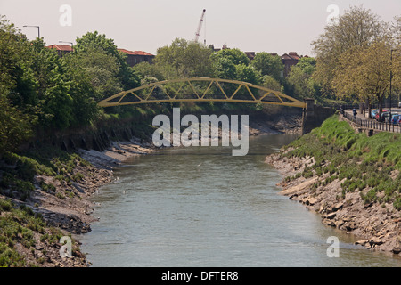 Ein Langstrecken Bild einer Fuß-Brücke überspannt eine Gezeiten Wasserstraße mit der Flut unter die Stahlkonstruktion. Stockfoto