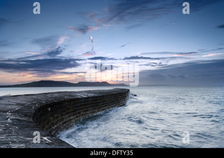 Die Sonne geht über The Cobb eine historische Hafenmauer bei Lyme Regis in Dorset einen kleiner Fischerhafen Stockfoto