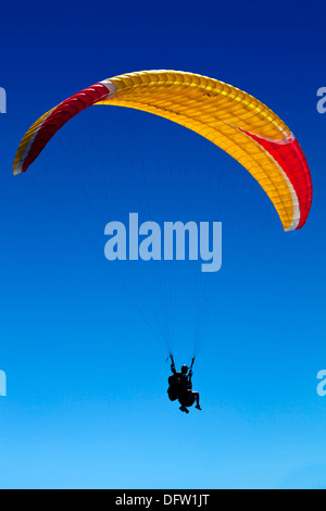 Rote und gelbe Hanglider vor einem strahlend blauen Himmel Stockfoto