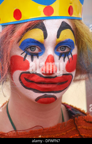 Eine Frau, die als trauriger Clown gekleidet ist und im September beim Bournemouth Arts by the Sea Festival, Bournemouth, Dorset UK, Clown-Make-up trägt Stockfoto