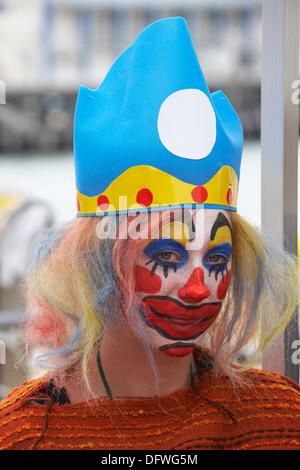 Eine Frau, die als trauriger Clown gekleidet ist und im September beim Bournemouth Arts by the Sea Festival, Bournemouth, Dorset UK, Clown-Make-up trägt Stockfoto