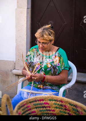 Portugal Algarve Loule Kunst & Kunsthandwerk Kunsthandwerksmarkt souvenir Neuheit artisan handwerklichen Marktstand Inhaber Frau mittleren Alters lady weben Warenkorb Stockfoto