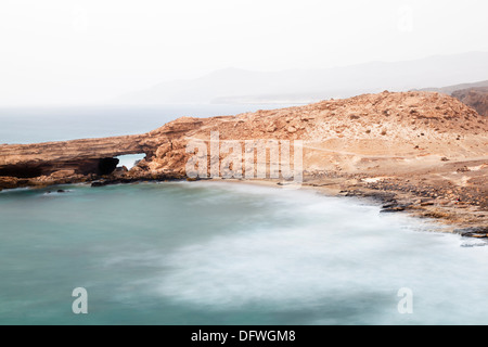 Langzeitbelichtung einer Bucht und einem natürlichen Felsbogen in La Pared, Fuerteventura, Spanien. Stockfoto