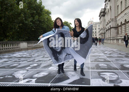 London UK. 9. Oktober 2013.  Zwei Mädchen tragen ihre Porträts auf der Terrasse im Somerset House geklebt werden. Eine Ausstellung des französischen Künstlers JR die riesige schwarze und weiße Bilder von Mitgliedern der Öffentlichkeit umfasst, werden in einem mobilen Studio montiert auf der Rückseite ein kleiner LKW fotografiert und sind außerhalb Somerset House in London Kredit angezeigt: Amer Ghazzal/Alamy Live-Nachrichten Stockfoto