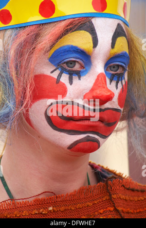 Eine Frau, die als trauriger Clown gekleidet ist und im September beim Bournemouth Arts by the Sea Festival, Bournemouth, Dorset UK, Clown-Make-up trägt Stockfoto