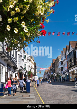 Guildford Shopper historischen High Street mit Sommerblumen und Union Flags genießen die Sonne Guildford Surrey UK Stockfoto