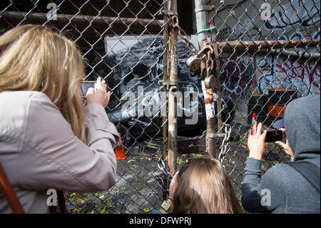 New York City, NY, USA. 9. Oktober 2013. Graffiti-Fans strömen in ein unbebautes Grundstück im Stadtteil Lower East Side von New York auf Mittwoch, 9. Oktober 2013, die neunte Ausgabe von Banksy-Graffiti-Kunst zu sehen. Diese besondere Ausgabe wird durch einen Maschendrahtzaun und einen verschlossenen Zaun angesehen. Bildnachweis: Frances Roberts/Alamy Live-Nachrichten Stockfoto