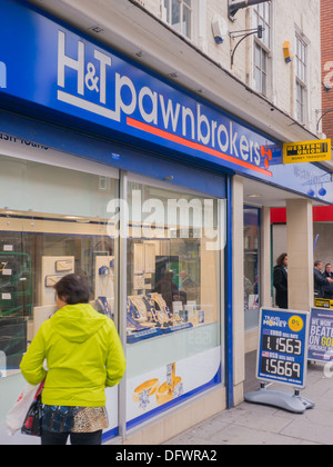 Frau im Fenster H & T Pfandleiher in Nottingham verpfändete Schmuck suchen. Stockfoto