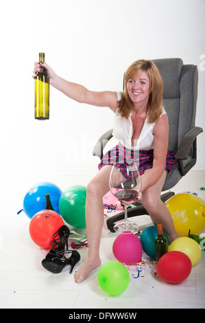 Weibliche Partei-Goer sitzen in einem Büro Stuhl Wein trinken und wirft die Flasche Stockfoto