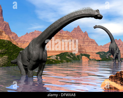 Zwei Brachiosaurus Dinosaurier im Wasser neben roten Felsen Berge an einem schönen Tag. Stockfoto