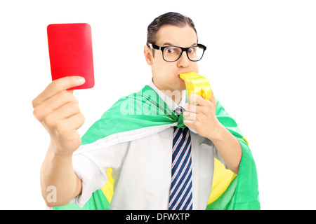 Euphorische männlicher Fan mit brasilianischen Verzögerung hält eine rote Karte und bläst eine Pfeife Stockfoto